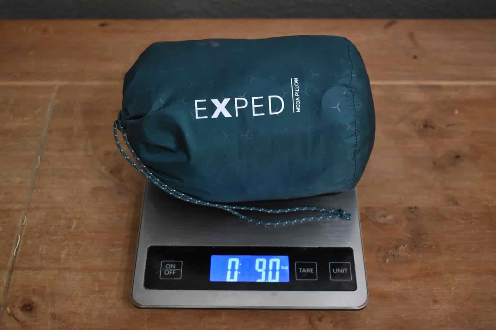 pillow in its stuff sack on a kitchen scale that reads 9 ounces
