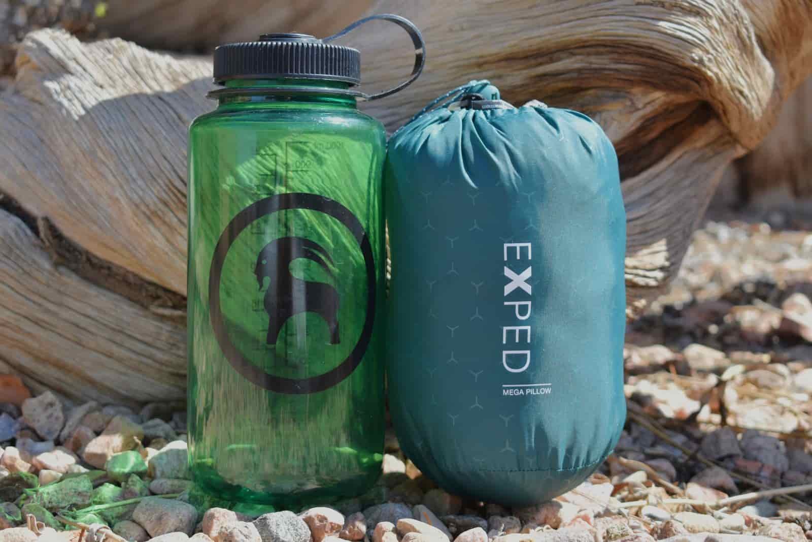 A Nalgene bottle and packed camp pillow sit by side for a size comparison