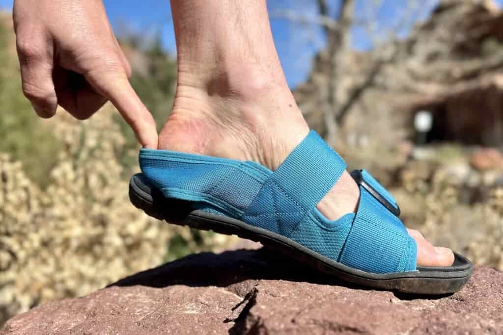 Close up profile image of a person's foot in a sandal lifted slightly at the heel.
