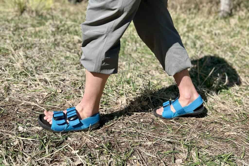 Close up image from the thighs down of a person walking in a grassy setting.