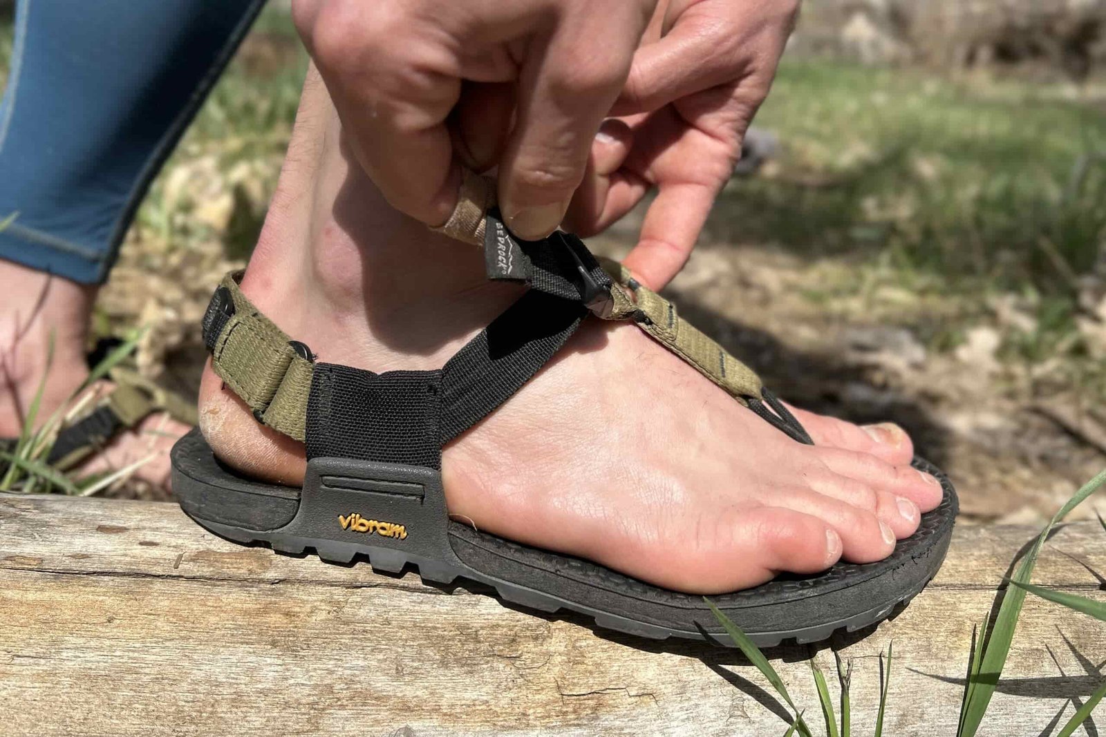 Close up image of a person adjusting a pair of hiking sandals.