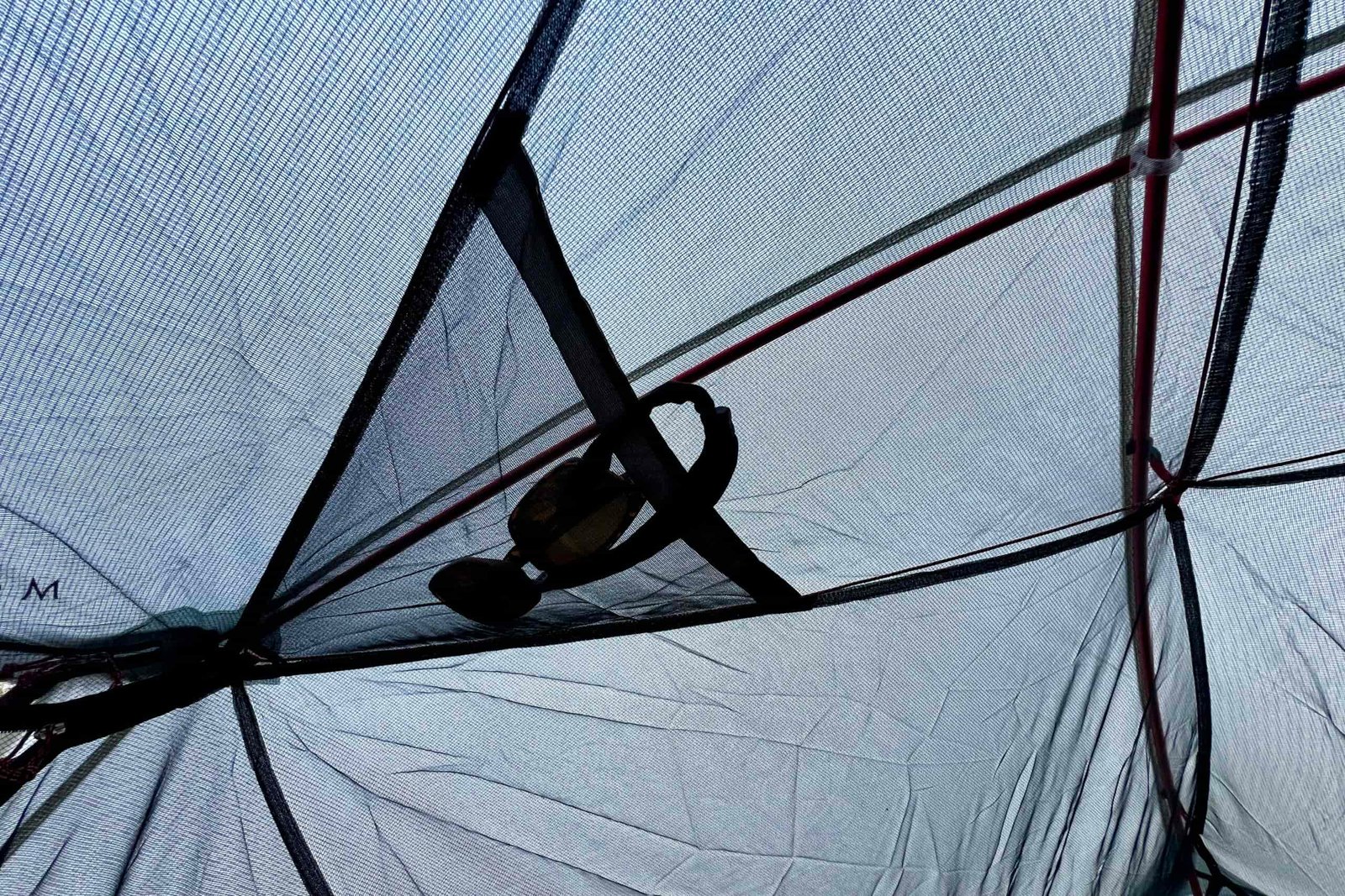 sunglasses stuffed in a mesh pocket of a tent ceiling