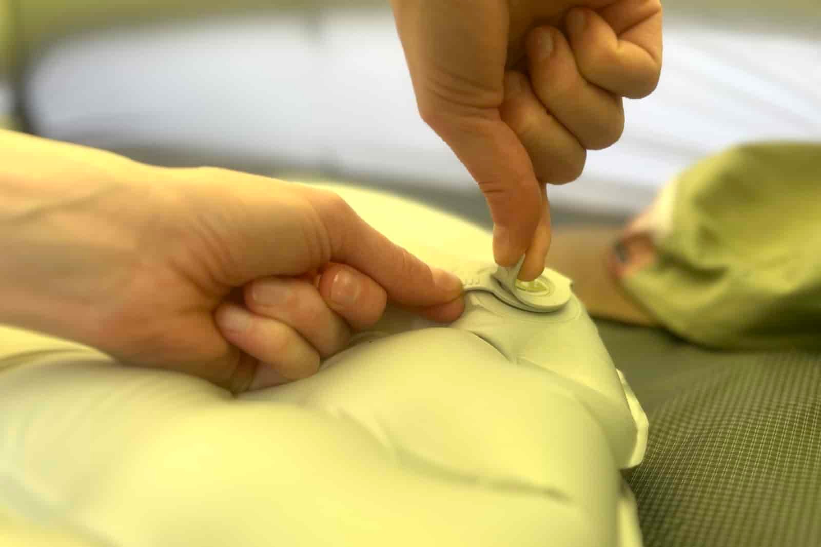 a closeup of a hiker opening the air valve on a sleeping pad
