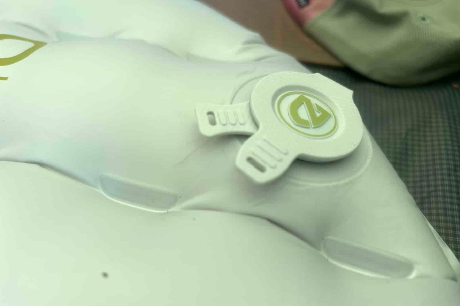 A close up of the air valve on a gray sleeping pad