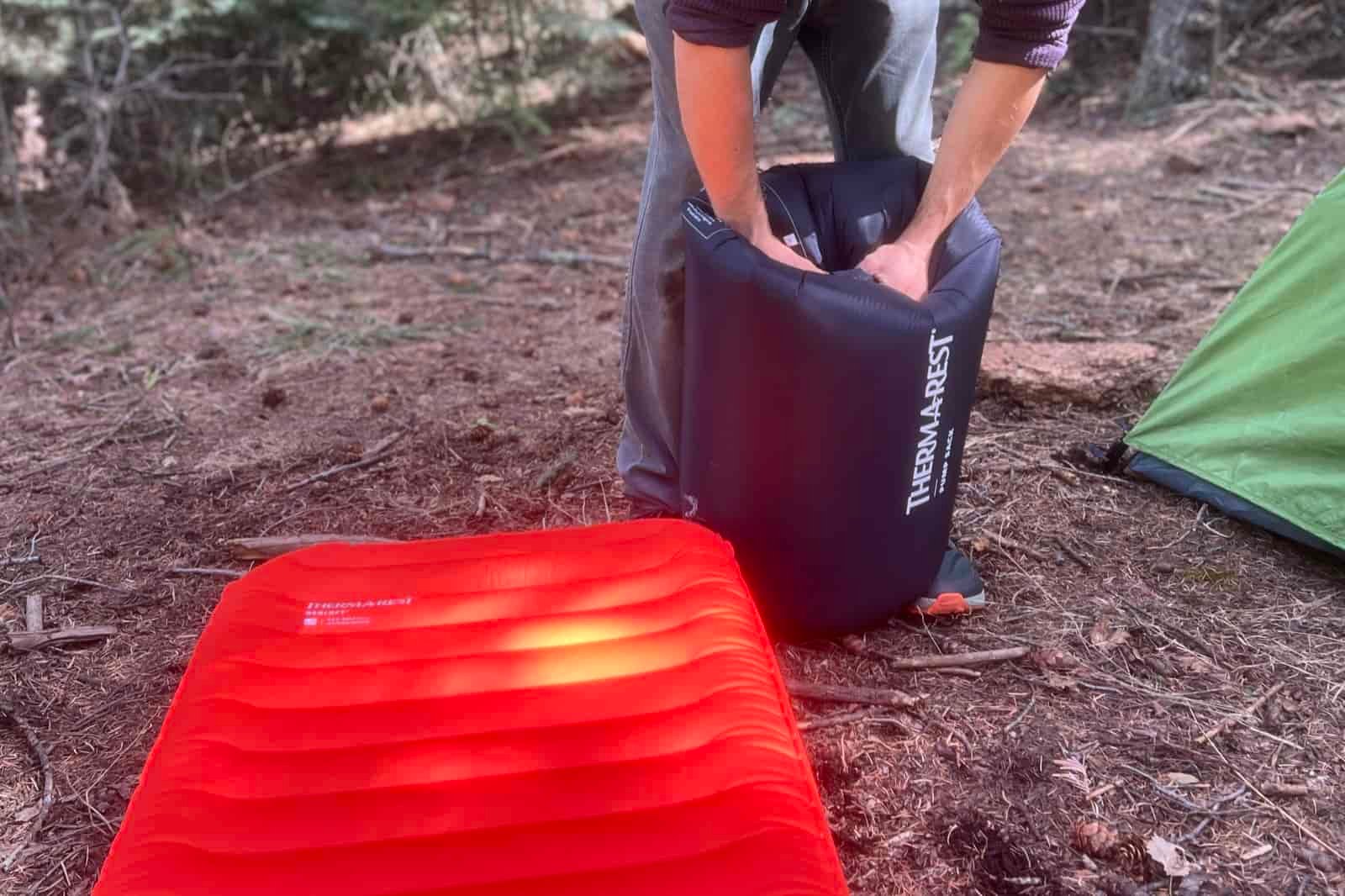 A closeup of a hiker pumping air into a sleeping pad with a pump sack