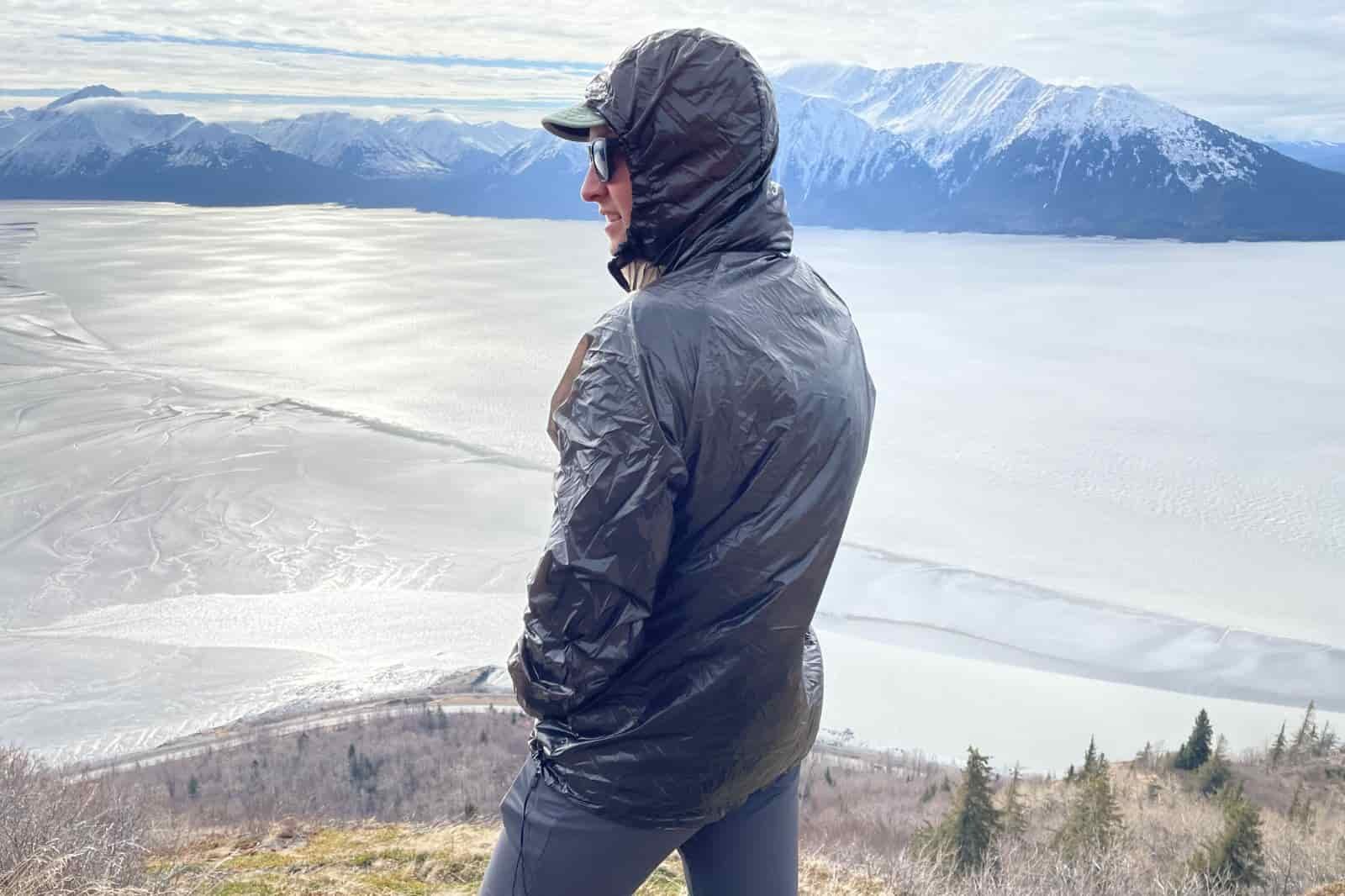 A man wears a windbreaker standing over a mountain view.