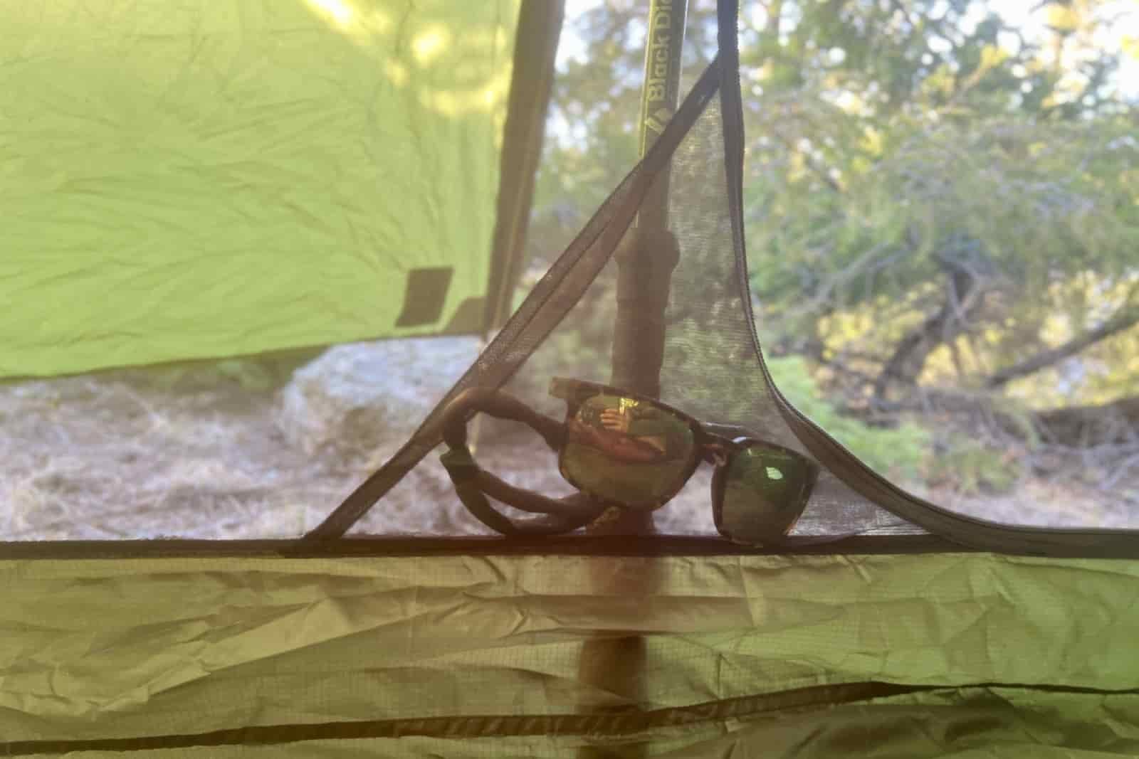 a close up of a pair of sunglasses in the small mesh pocket of a tent