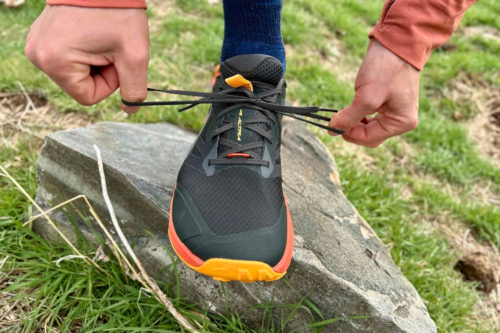 Close up image of a trail running shoe from the front as a person tightens the laces.