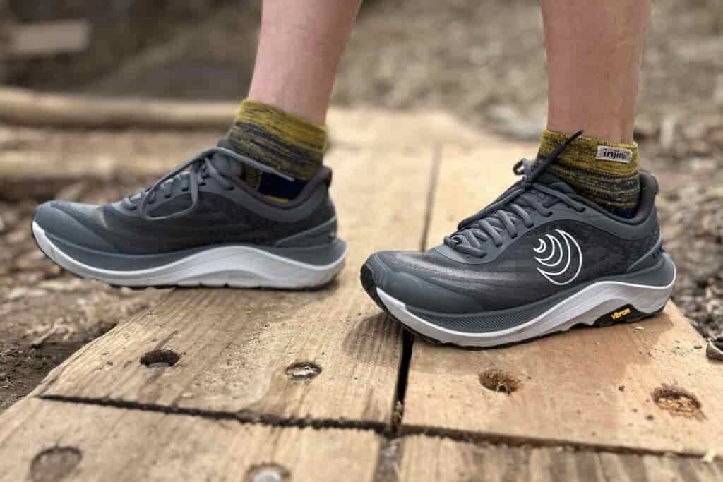 Close up from the knees down of a person wearing trail runners.