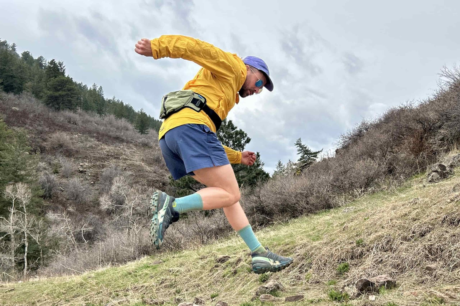 A man jumps in the air, with his legs and arms kicked out wearing running attire.