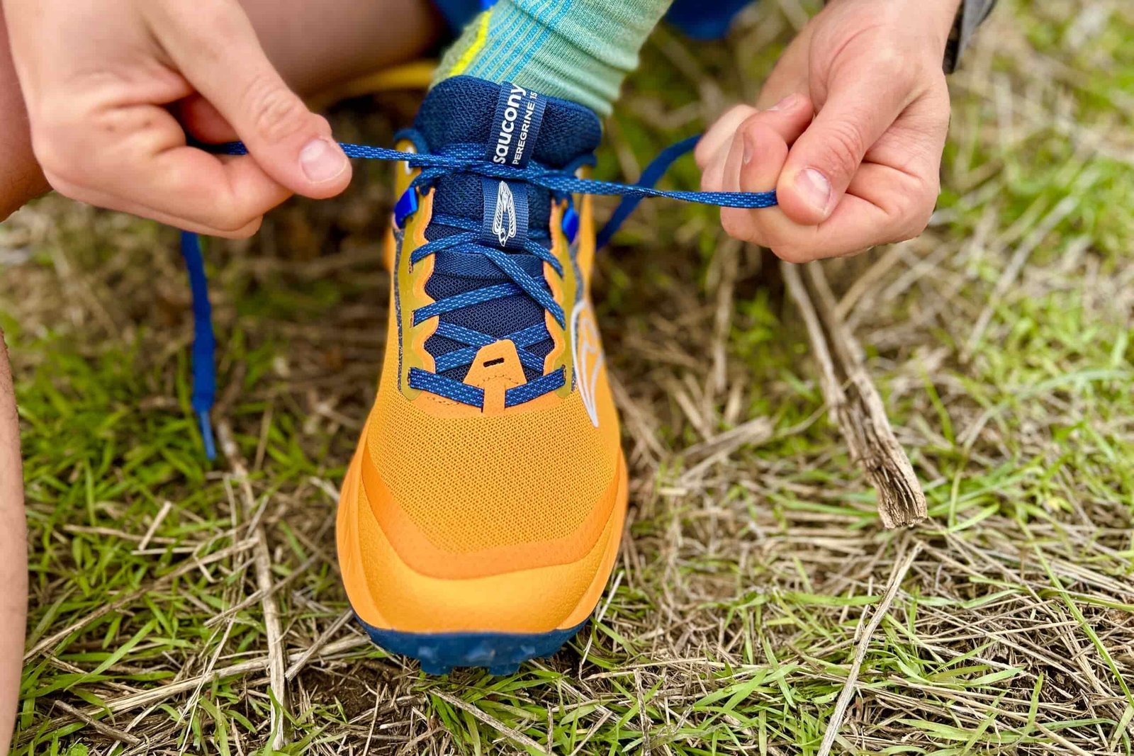 Close up image of a pair of hands tying the laces of a trail runner.