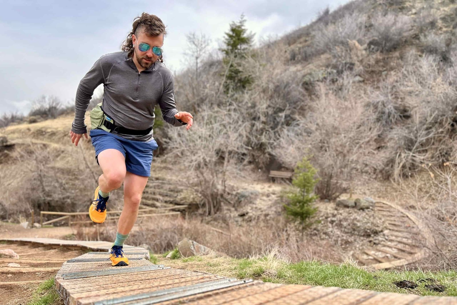 A man runs uphill on a wooden section of trail.