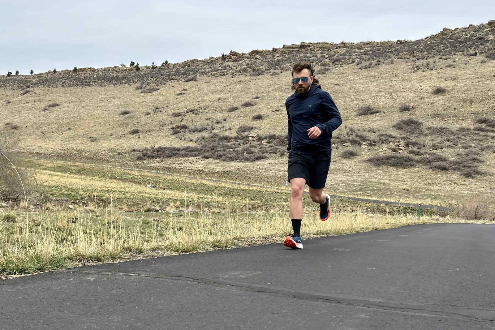 A man runs along a road in a mountain setting.