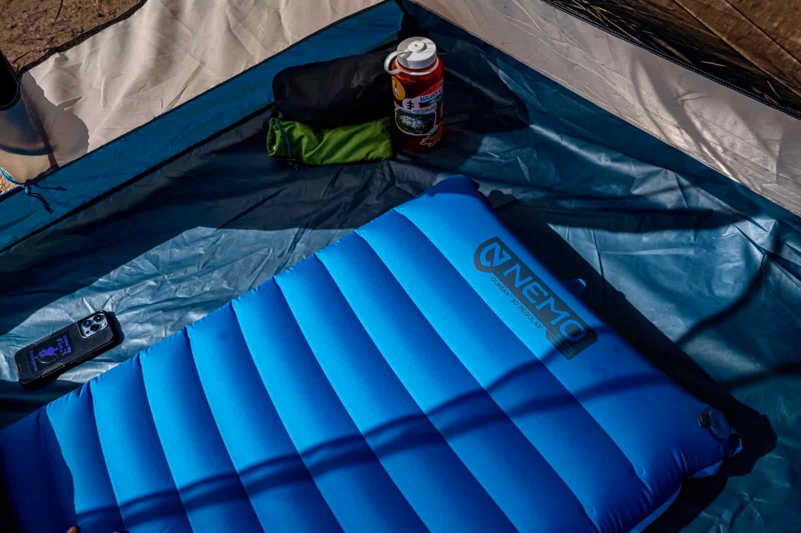a blue sleeping pad in a tent with other gear around