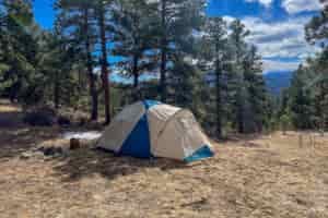 A side view of a tent with blue skys and mountains in the background.