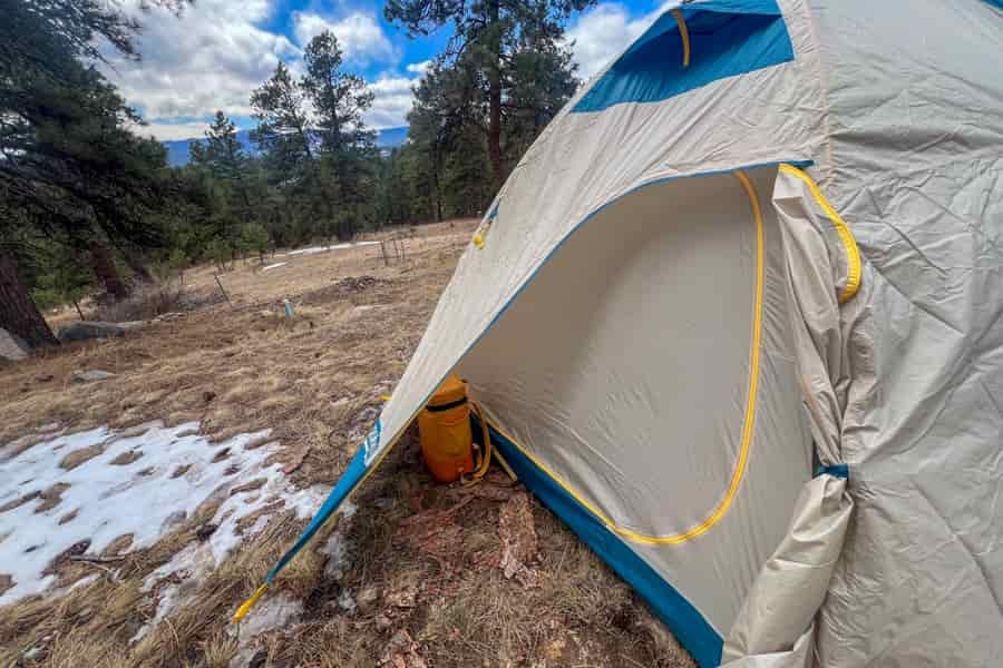 The rear vetibule of a tent with a small backpack cooler inside the vestibule.