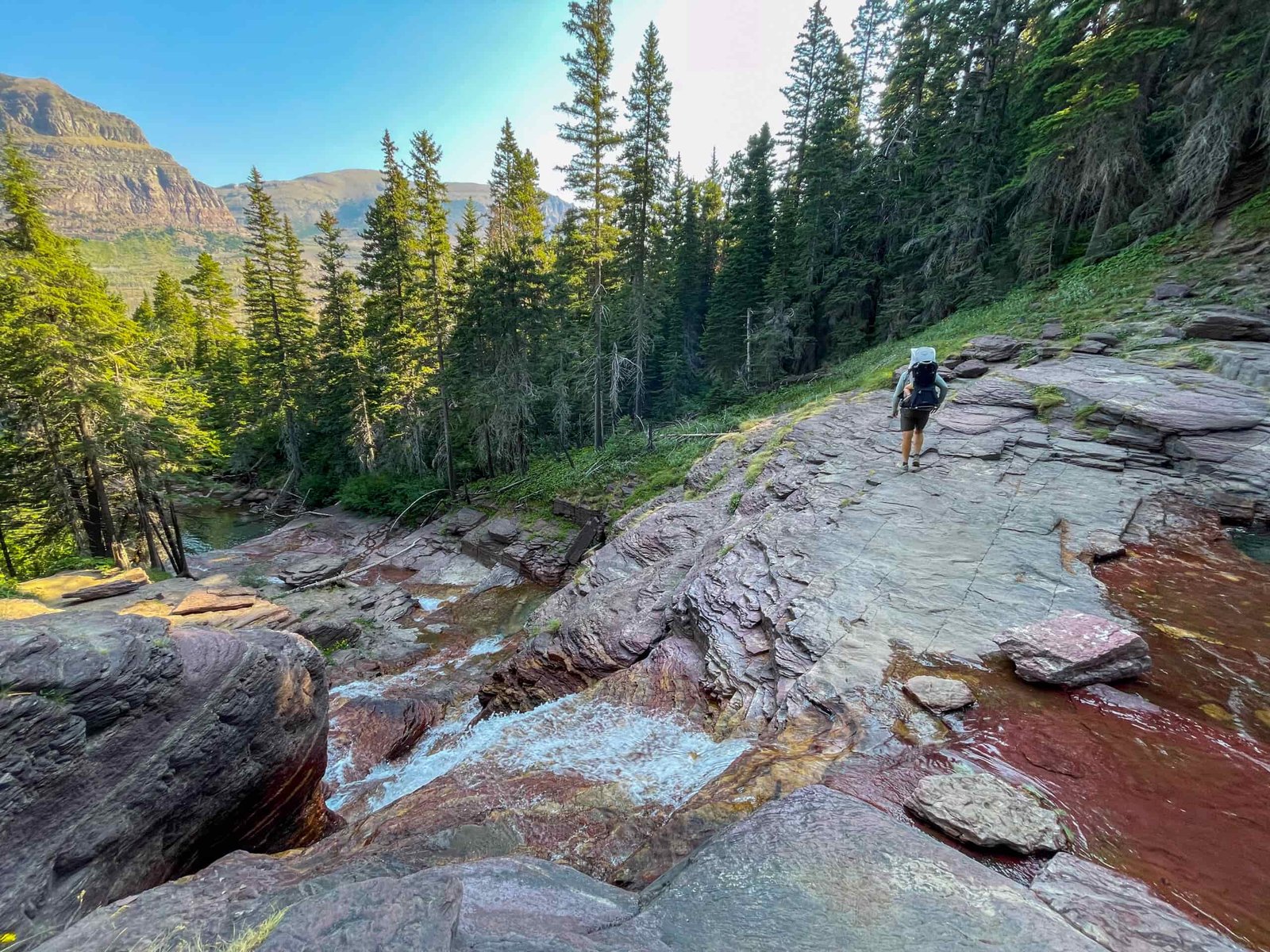 a man on top of a waterfall carrying a child in a backpack