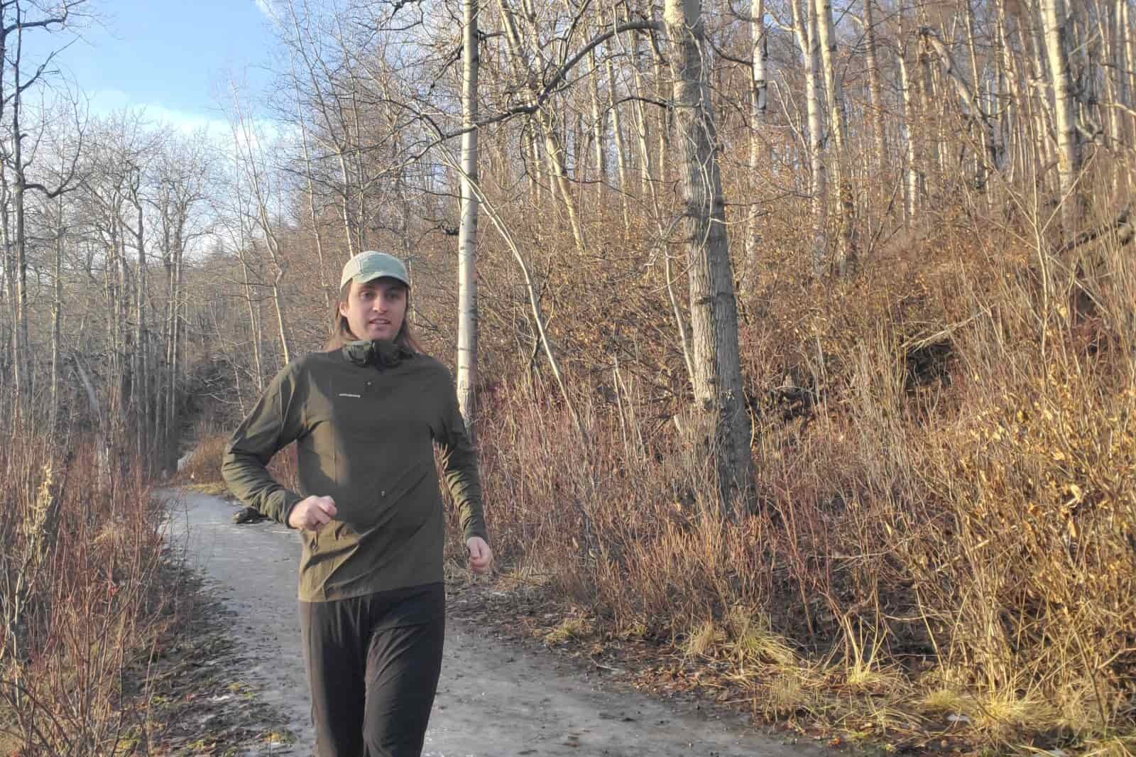 A man runs up a hill on a muddy trail.