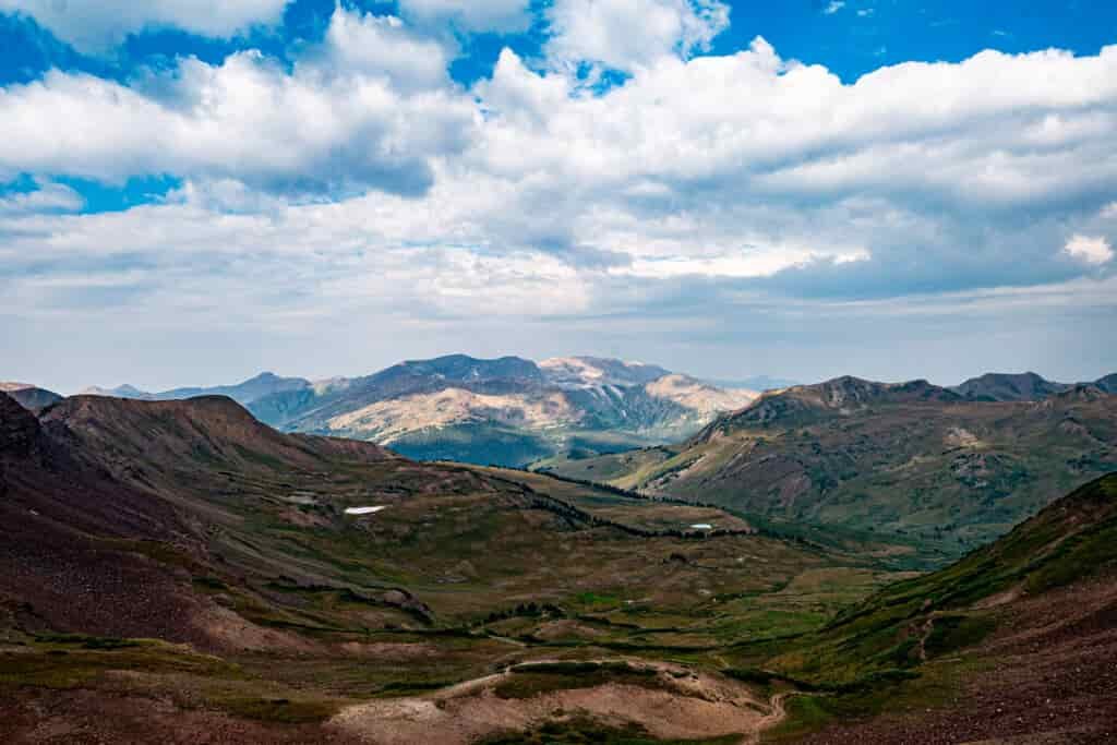 A wide open valley takes up most of the foreground with some mountain peaks in the distance.