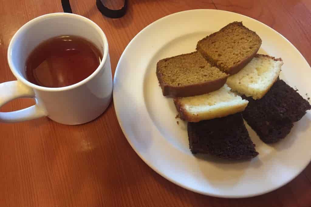 Close up of a cup of tea and three tea cakes on a dish.