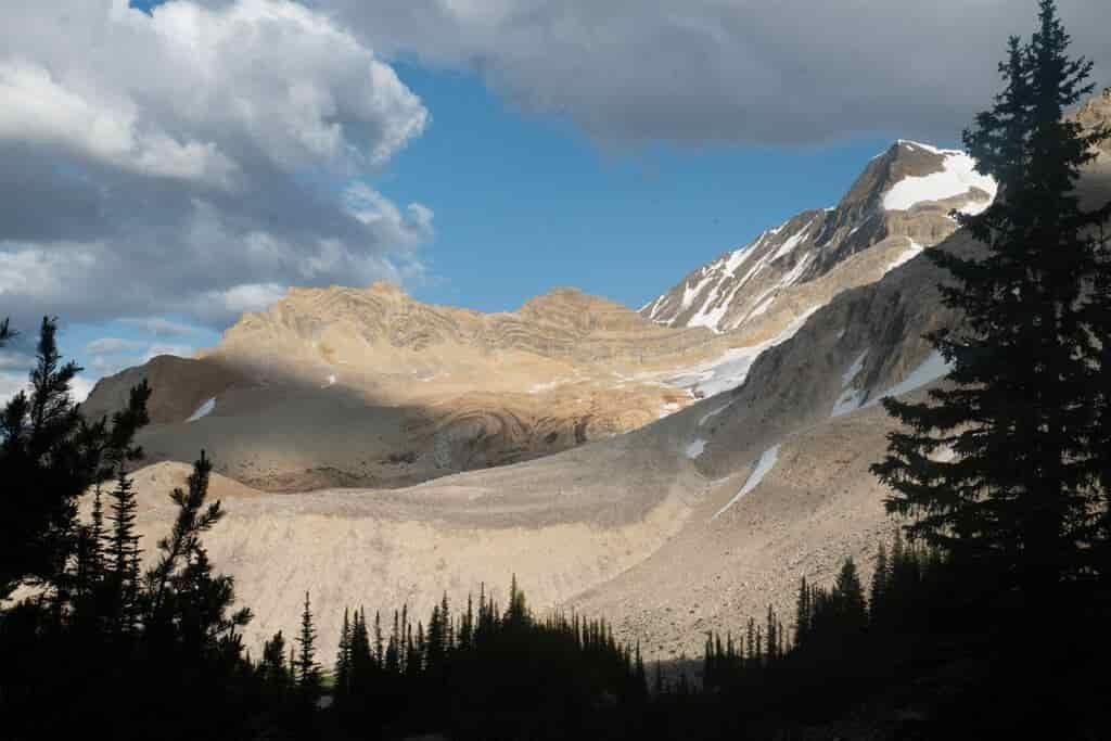 Late afternoon light glows on the side of a rocky mountain.