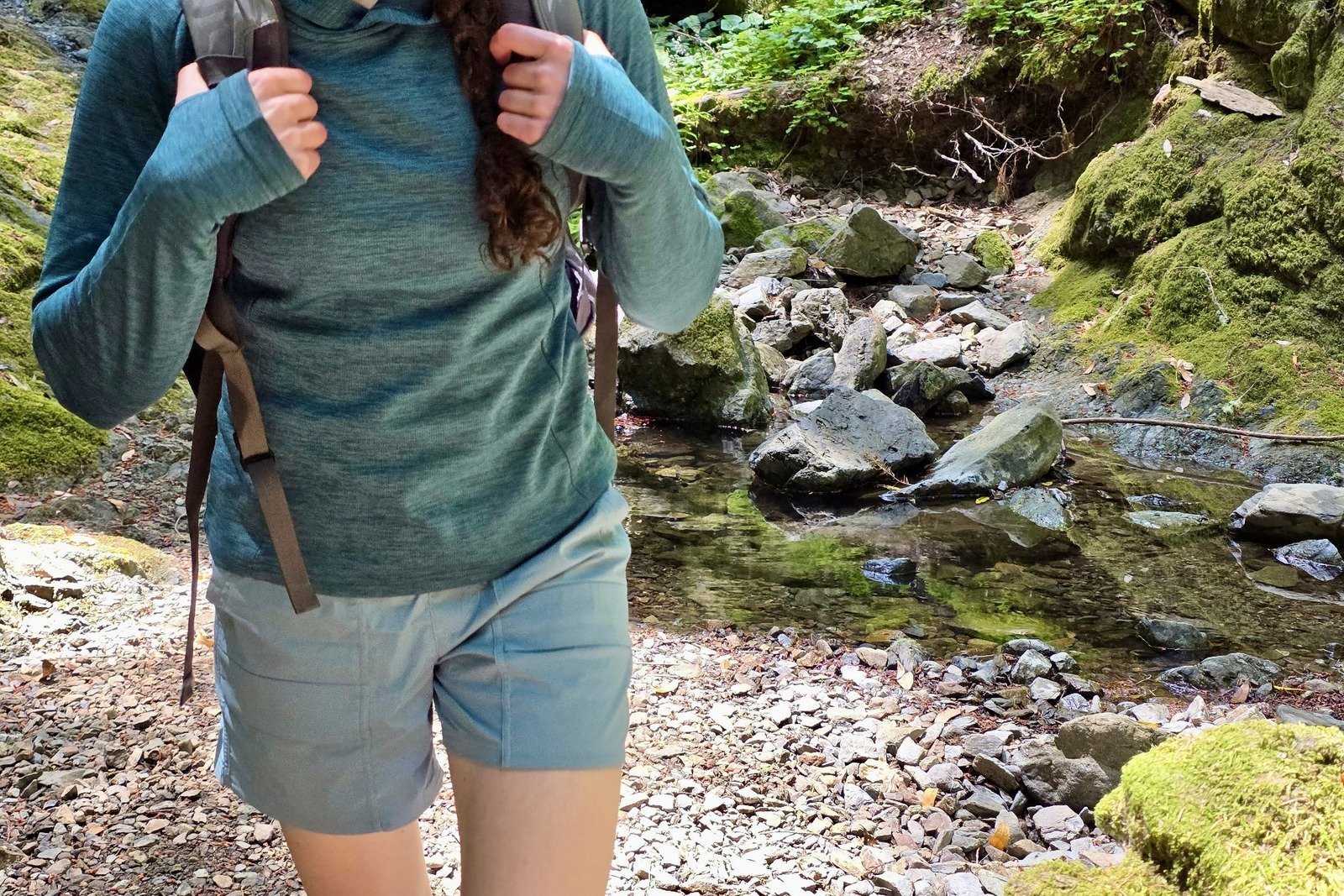 Woman hiking with a pack, focusing on a close up of her hiking shorts.
