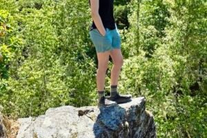 Woman standing on a rock outcropping overlooking the scenery below.