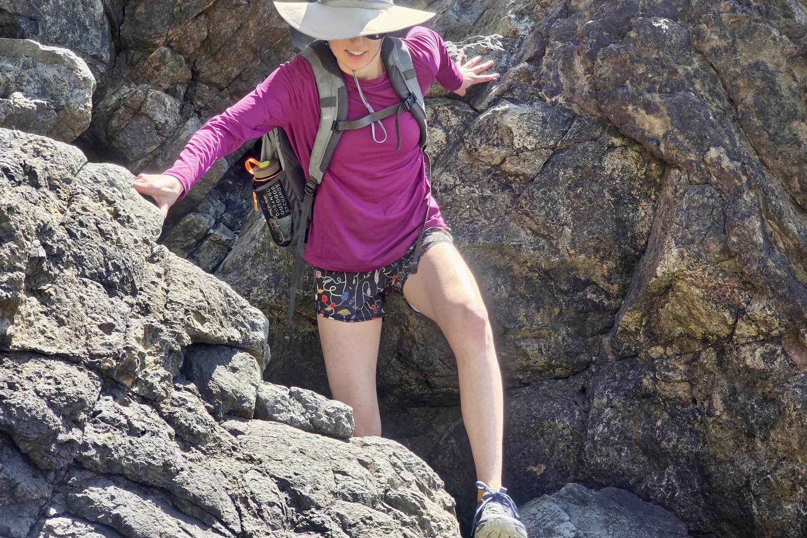 A woman hikes and scrambles in rock terrain.