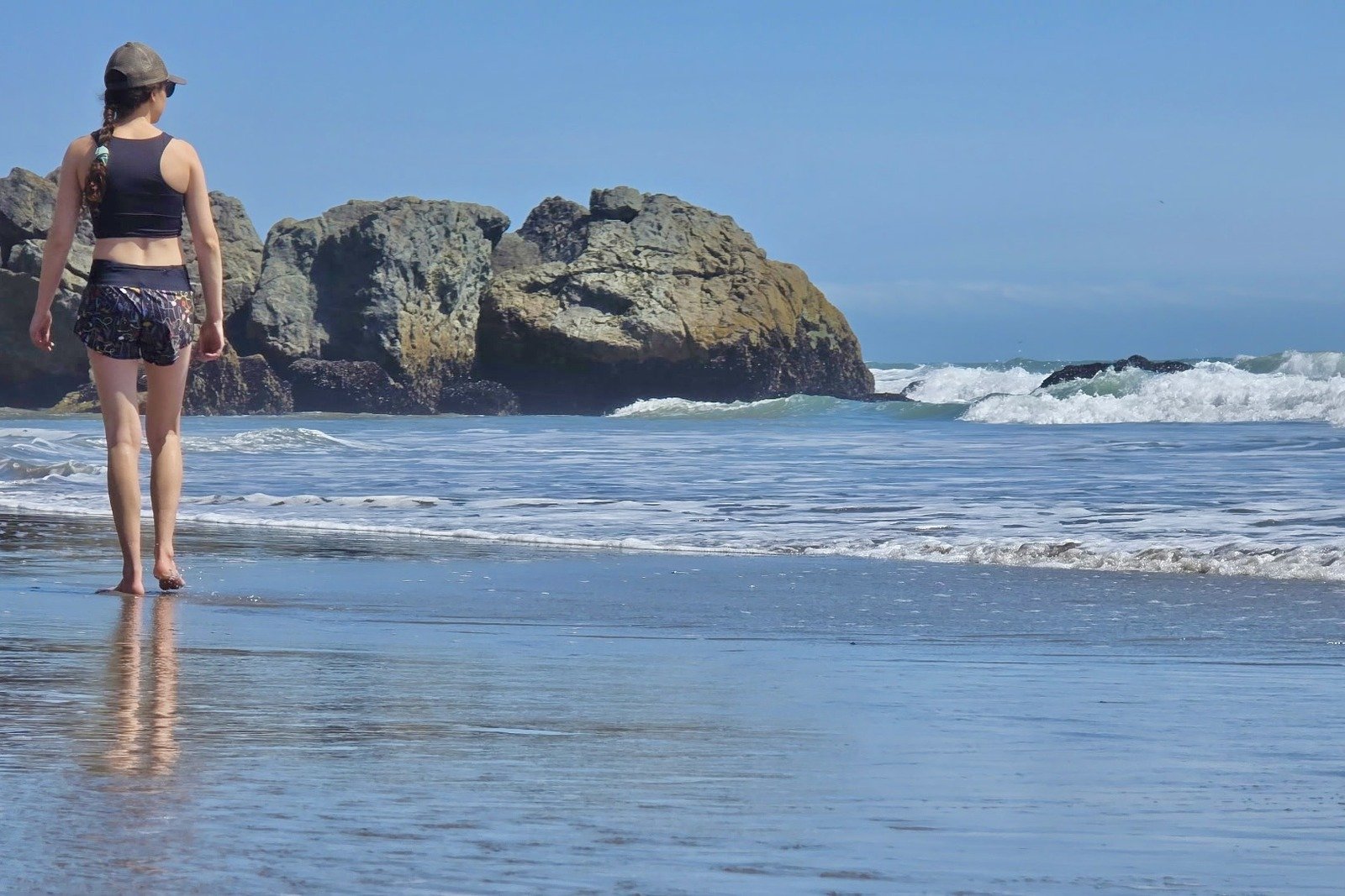 A woman walks along the beach in her Oiselle shorts.