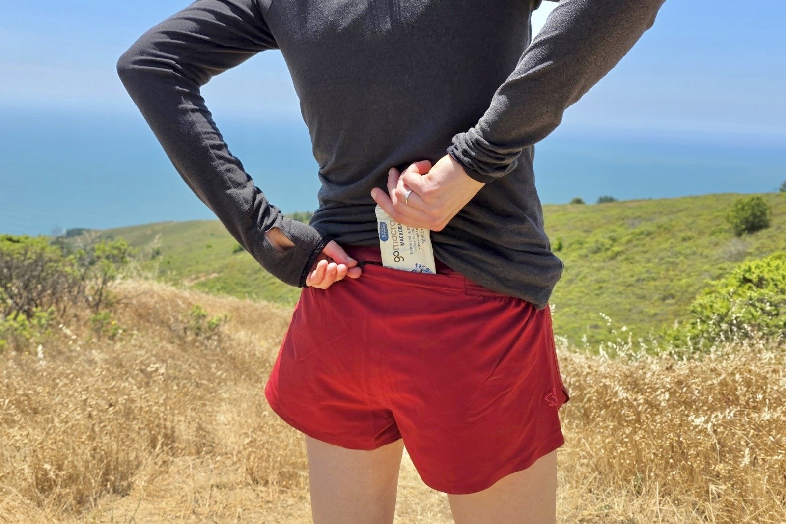 A woman slides a protein bar into the back zippered pocket of her shorts