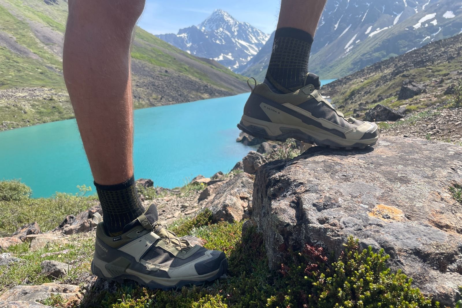 A closeup of shoes in front of an alpine lake.