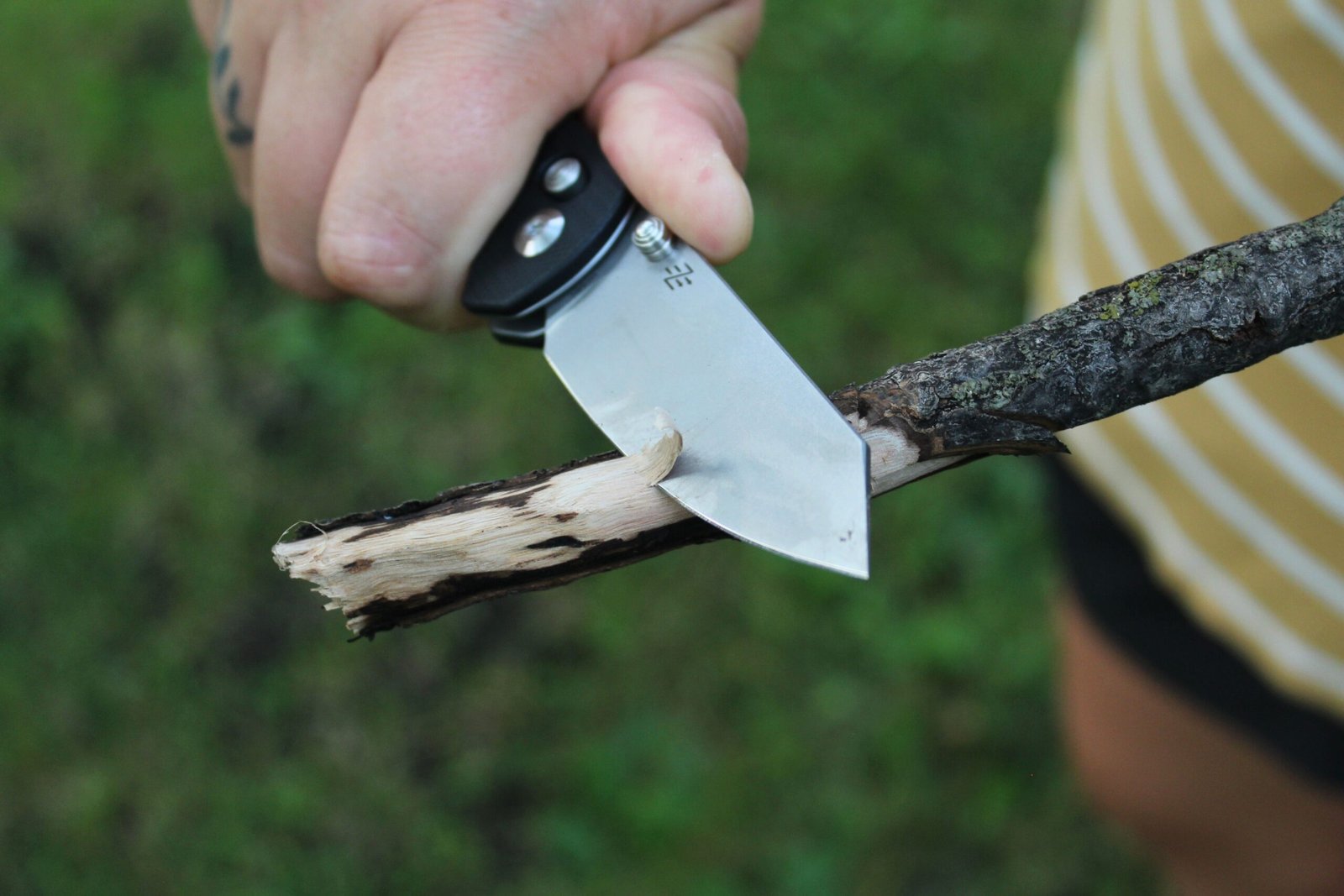 Close up of someone shaving down a stick using the Civivi Yonder G10 Pocket Knife
