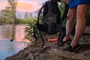 A person holds a black Decathlon Quechua daypack by the backstrap, giving a view of the padded back panel.