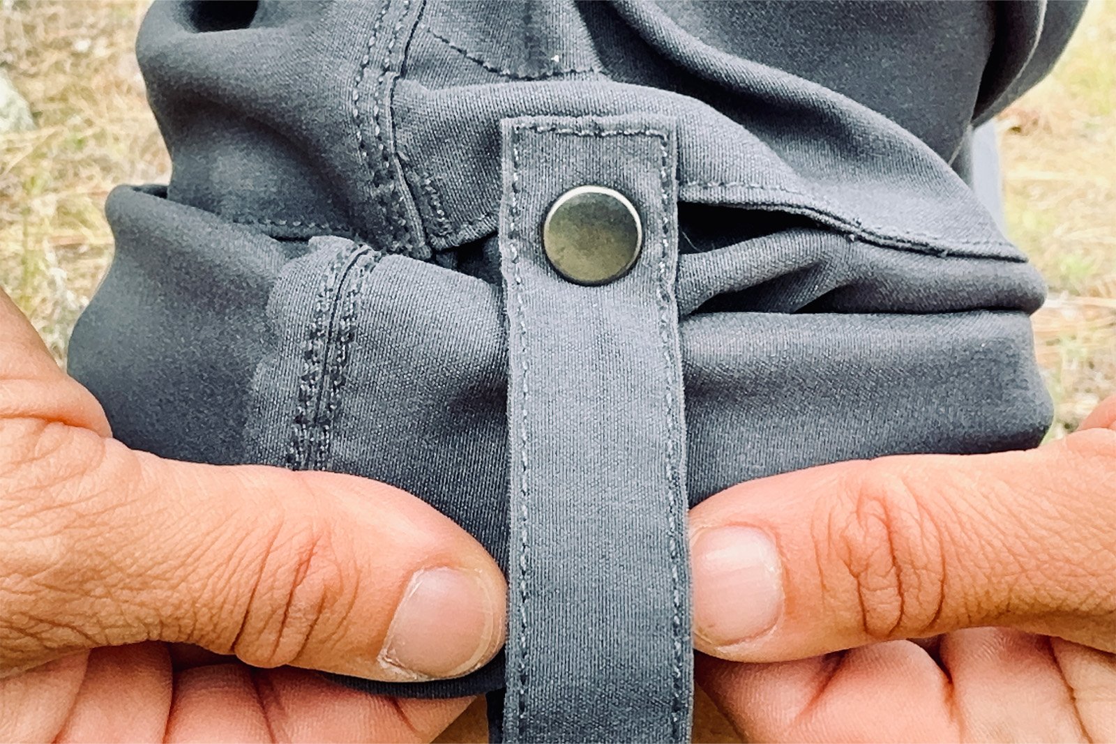 Close up of two hands holding the rolled up Duluth pants cuff with the snap features shown prominently.