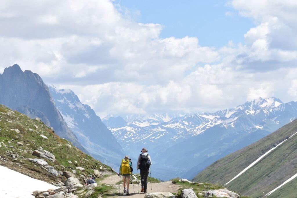 Two retirement-age hikers enjoy a scenic trail down to a valley in the Italian Alps