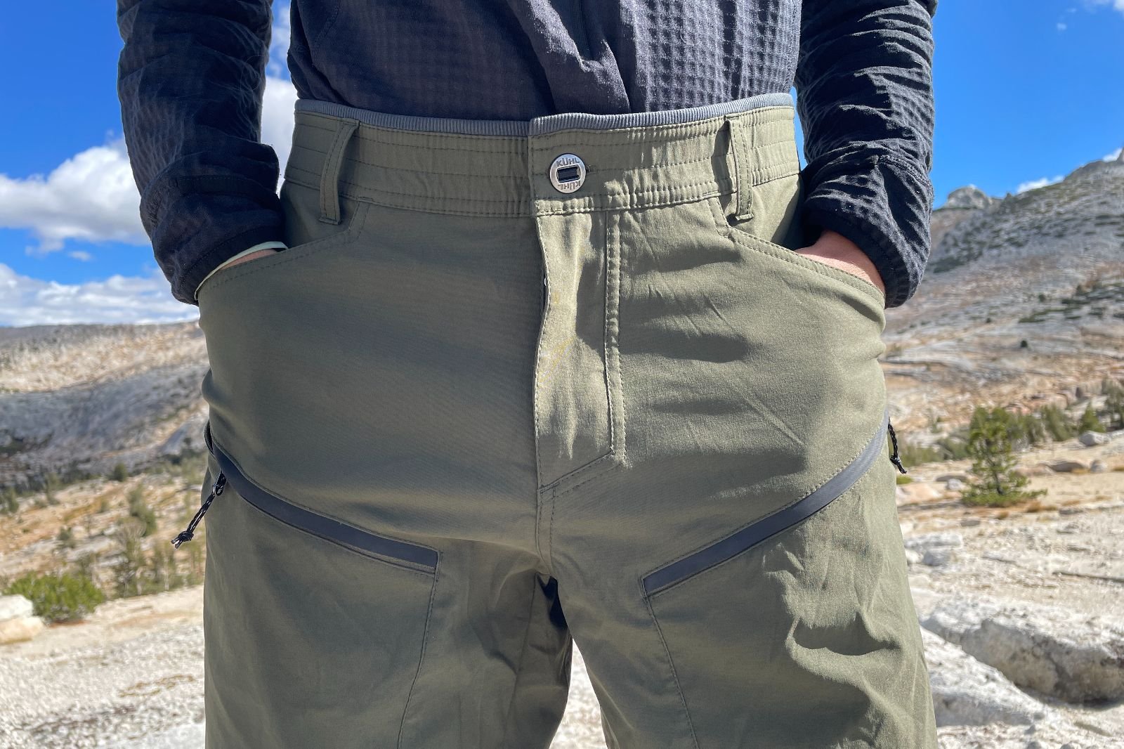A closeup of the front of a pair of green hiking pants.