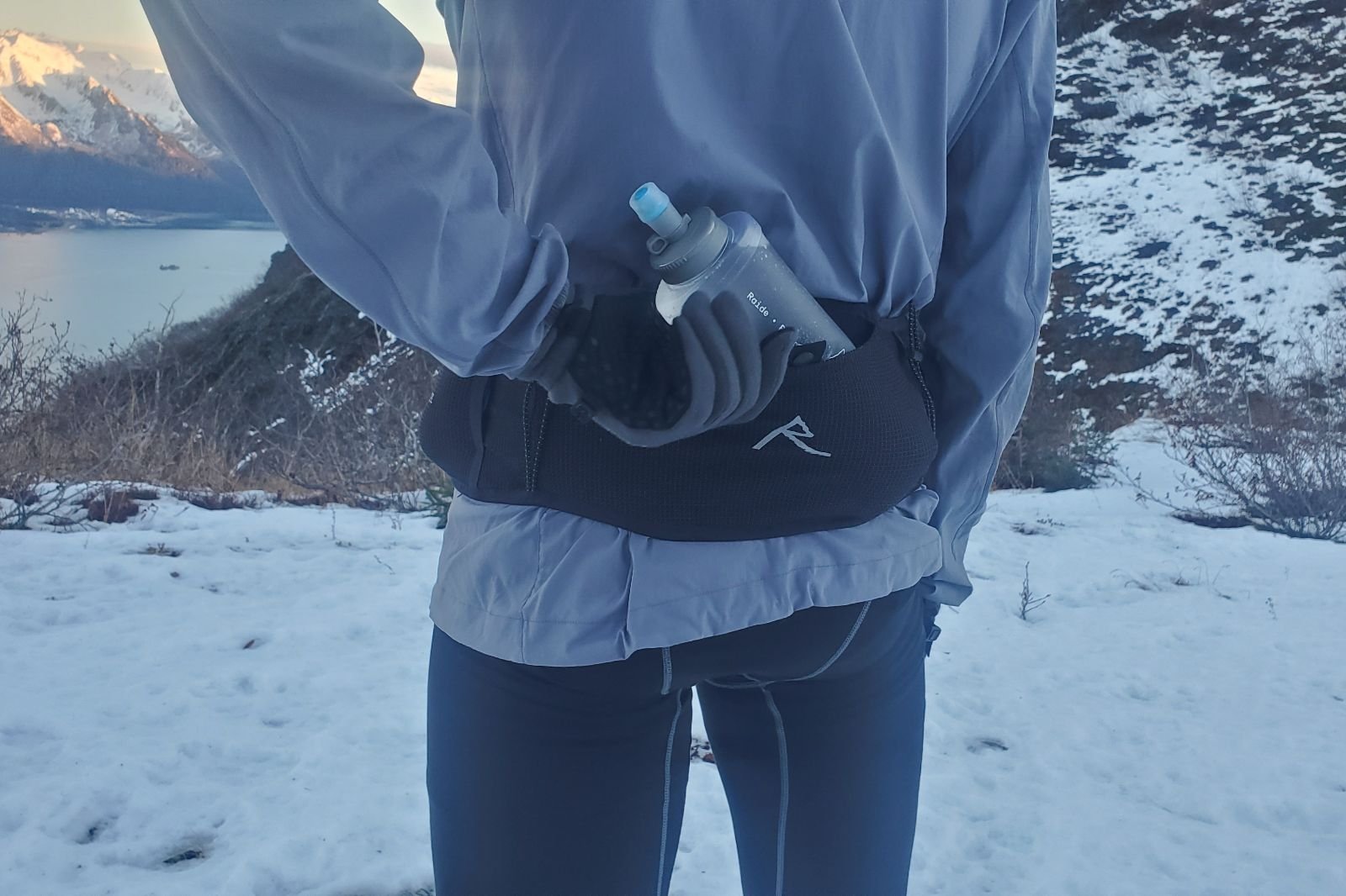 A closeup of a gloved hand grabbing a water bottle.