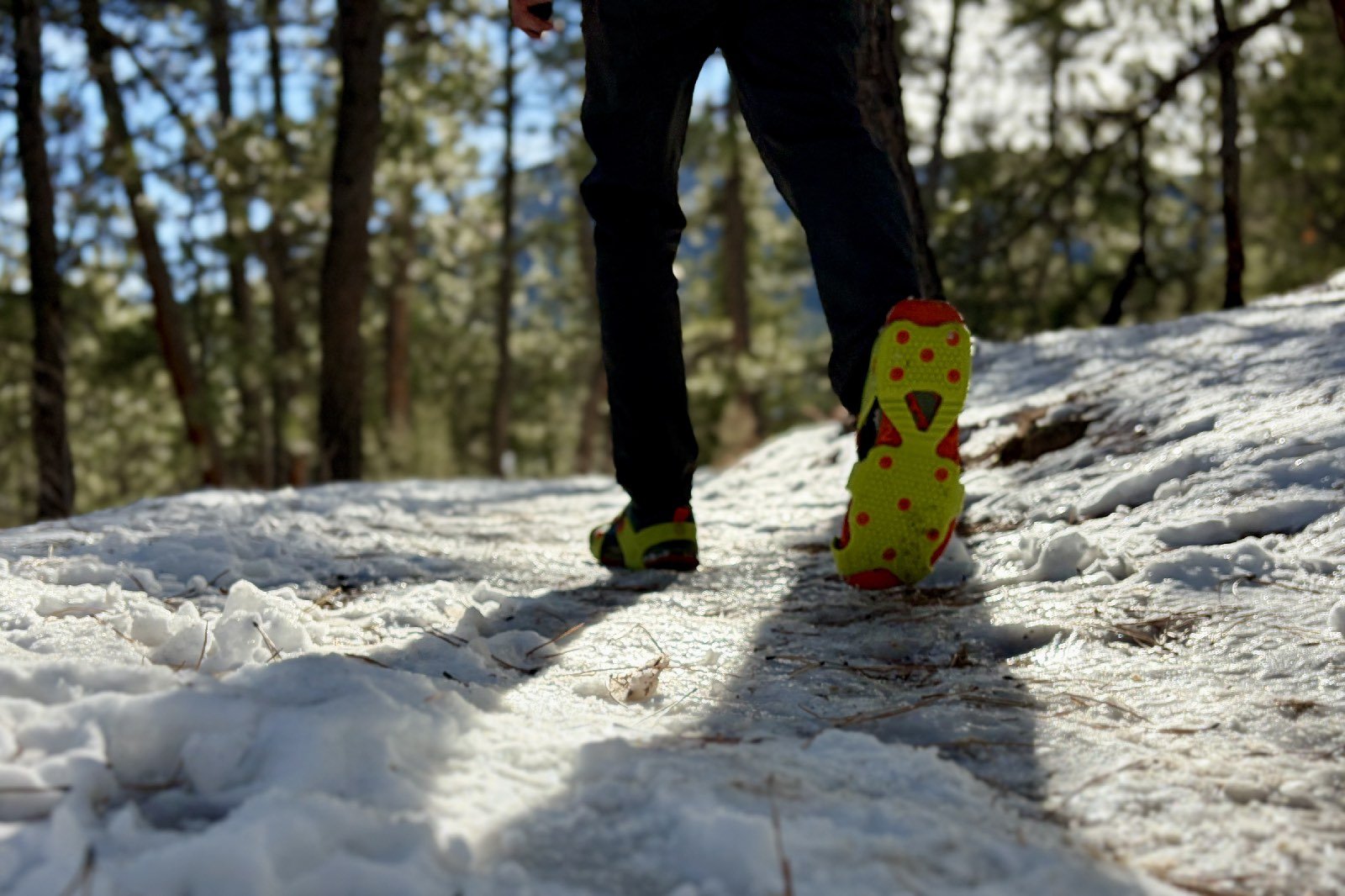 a hiker walks away from the camera showing the bottom of one shoe with a traction device attached