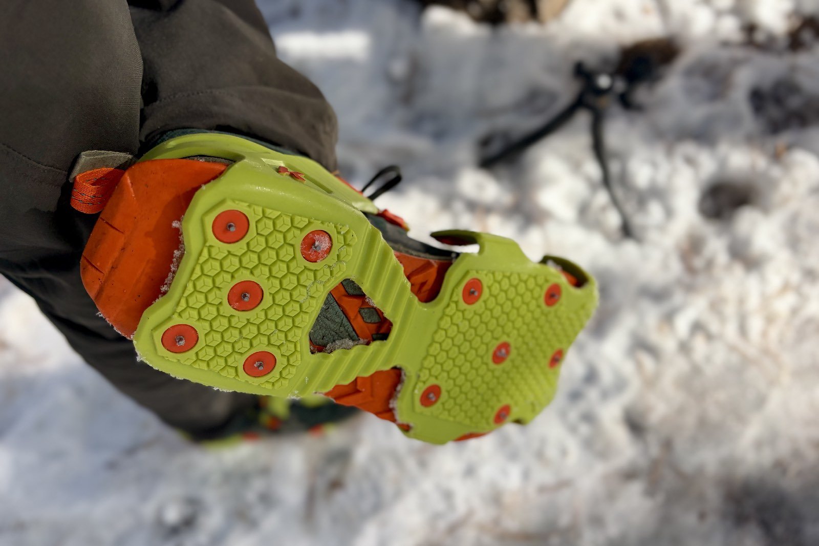 a POV view of a hiker lifting his shoe to show the bottom of his ice cleats