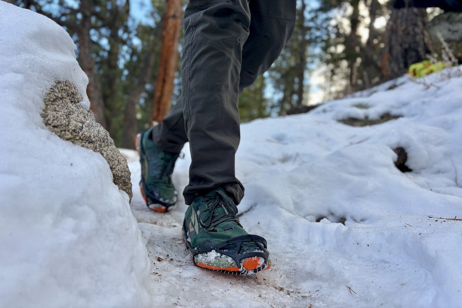 a waist down view of a hiker walking on a snowy trail towards the camera