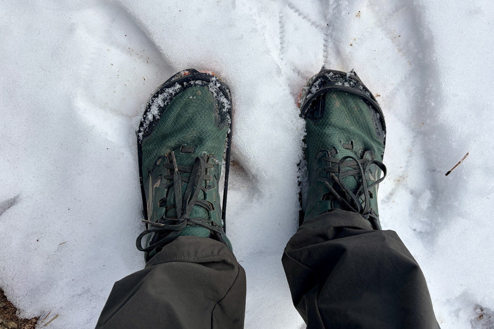 a POV view of a hikers feet with trail runners and ice cleats