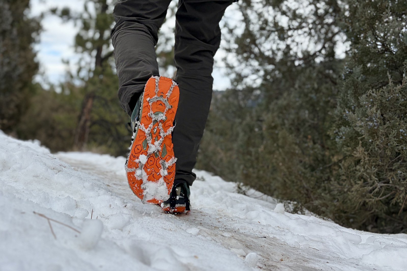 a hiker walks away from the camera with the bottom of his shoe showing a pair of micro spikes.