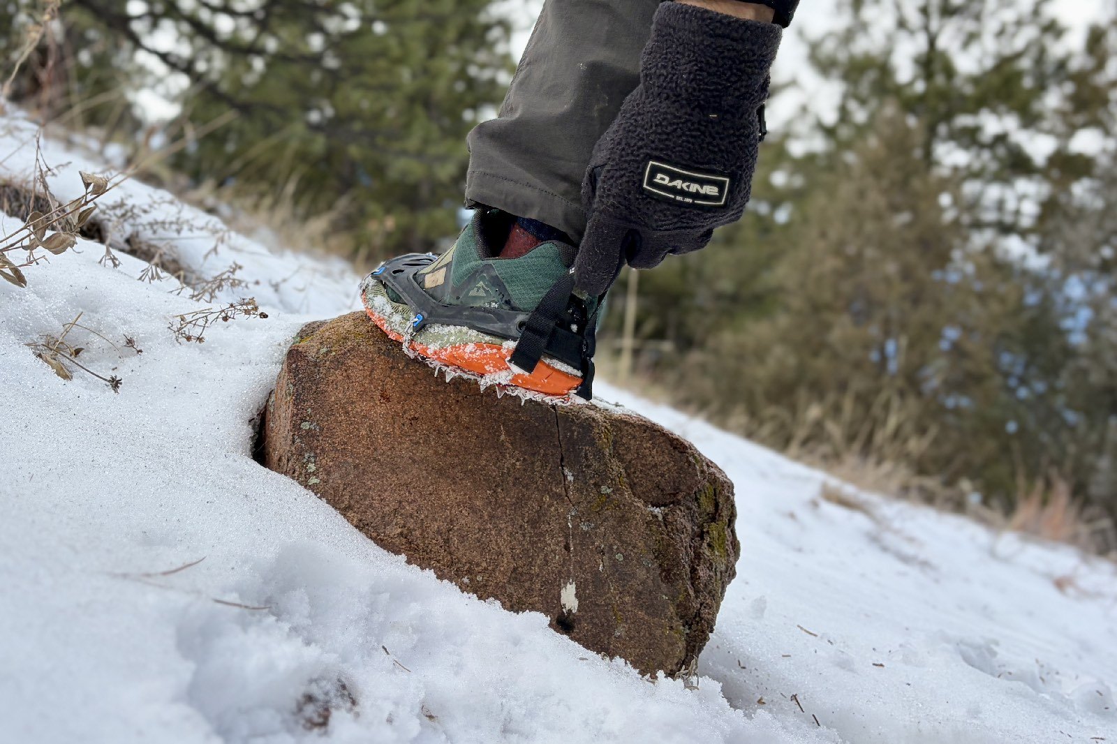 a close up of a hiker pulling on a pair of ice cleats with the heel pull tabs