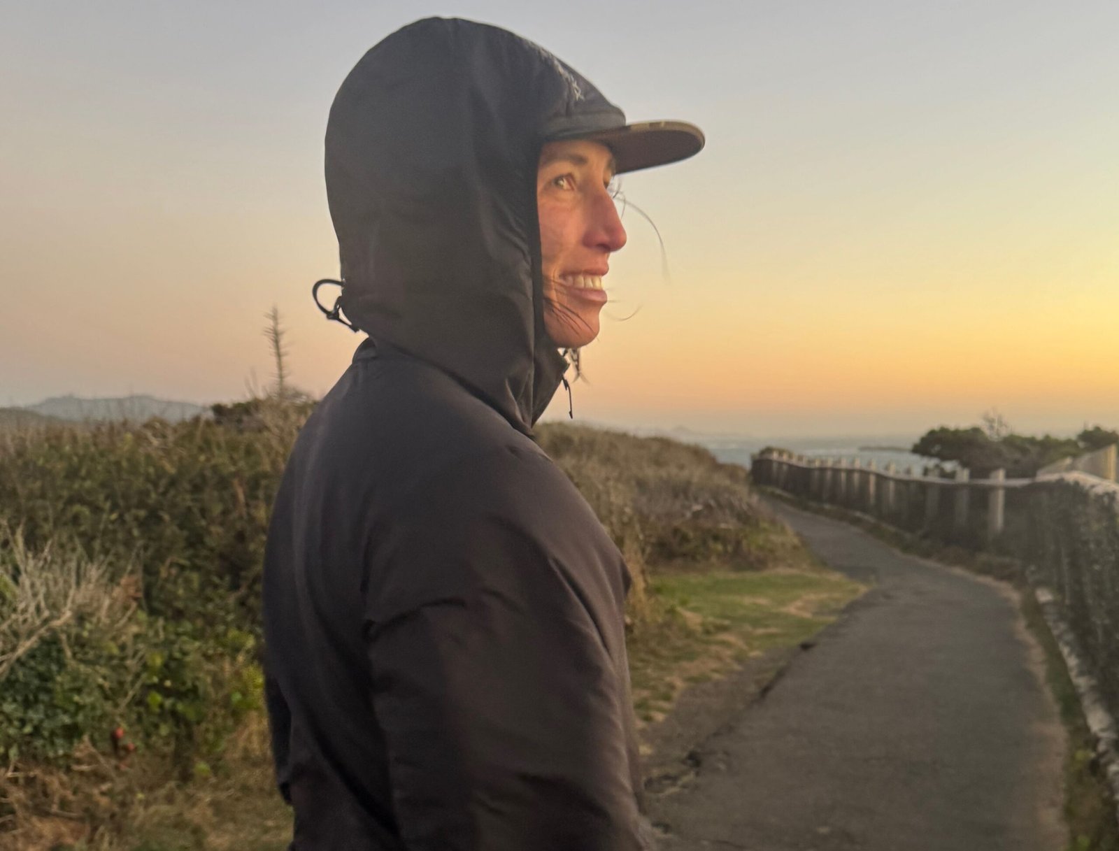 woman smiles while watching the sunset on the oregon coast